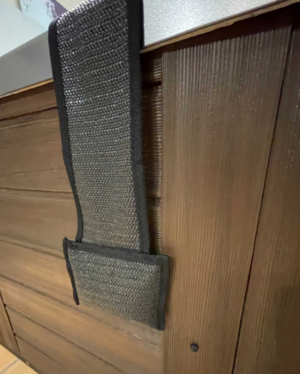 Close-up of a weighted hot tub pillow hanging over the edge of a wooden hot tub.