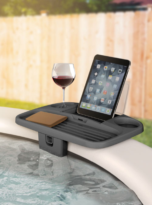 Adjustable spa tray table with waterproof compartment, holding a tablet and wine glass by a hot tub.